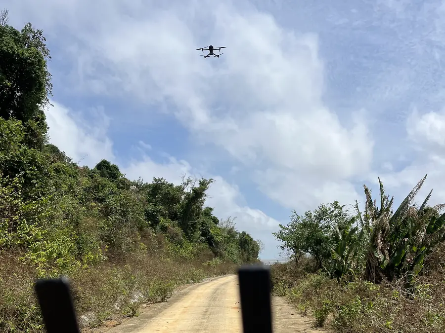 UAV flying over a hill road, with dense forest covering the slopes on Hon Khoai Island