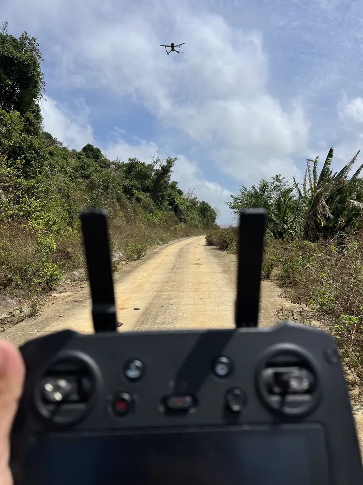 UAV flying a topographic survey over a hill road through forest on Hon Khoai Island, Ca Mau