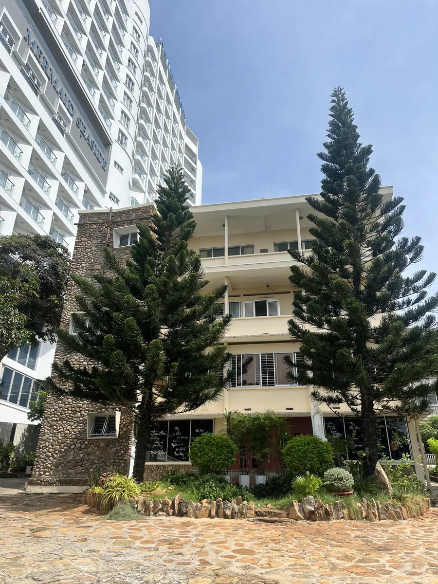 Khối nhà nhiều tầng và hai cây thông ở sân trước Betania Bãi Dâu